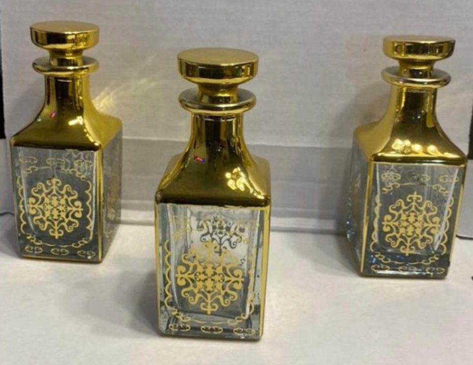 Three ornate gold and glass perfume bottles with intricate designs.